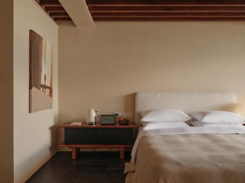 a bedroom with a bed with white pillows and a table at 大理空岛半山海景民宿 in Dali