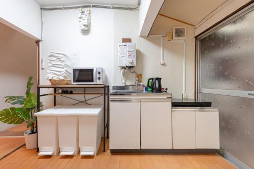 a kitchen with white cabinets and a microwave at 東上野戸建 in Tokyo