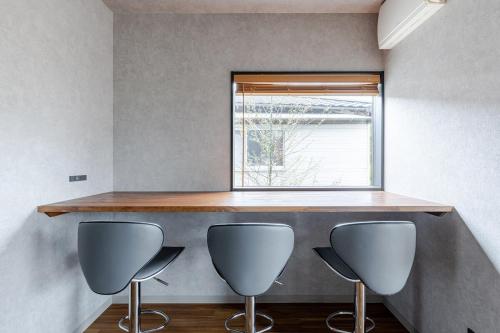 a kitchen with three chairs and a counter with a window at 宰府旅館b棟 in Dazaifu