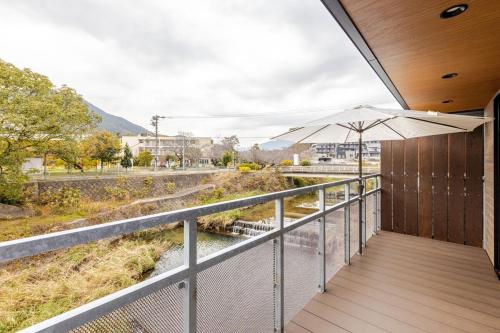 a balcony with an umbrella overlooking a river at 宰府旅館b棟 in Dazaifu