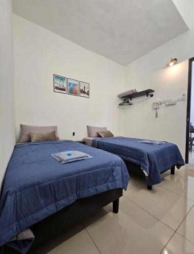 two beds in a white room with blue sheets at V-Home Taiping, 3BR, 7pax, Full Aircond, Wifi & Netflix, Early Bird Promo in Taiping