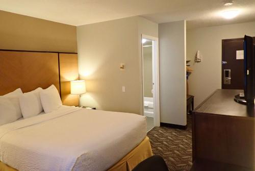 a hotel room with a bed and a bathroom at Days Inn by Wyndham Airdrie in Airdrie