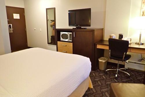 a hotel room with a bed and a desk and a television at Days Inn by Wyndham Airdrie in Airdrie
