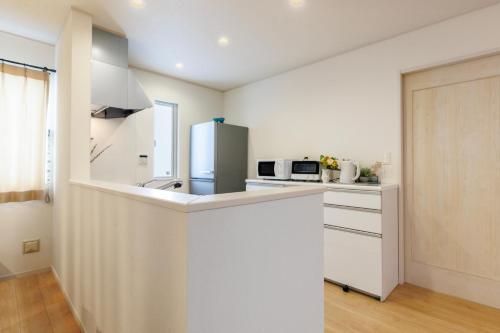 a white kitchen with a refrigerator and a microwave at 恩納村一棟貸し ビーチや飲食店徒歩圏内 最大6名 Ciel希望ヶ丘A棟 in Onna