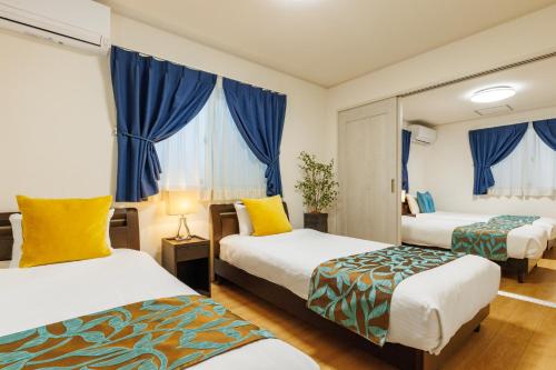 a hotel room with two beds and blue curtains at 恩納村一棟貸し ビーチや飲食店徒歩圏内 最大6名 Ciel希望ヶ丘A棟 in Onna