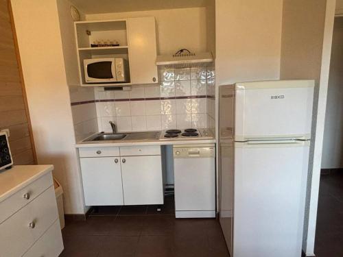 La cuisine est équipée d'un réfrigérateur blanc et d'un four micro-ondes. dans l'établissement Appartement 3 pièces calme avec parking et balcon, Les Angles - FR-1-593-125, aux Angles
