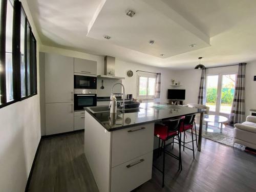 une cuisine avec des placards blancs et un îlot de cuisine avec des chaises rouges dans l'établissement Appartement calme à Hasparren avec jardin et Wi-Fi, 4 couchages - FR-1-495-144, à Hasparren