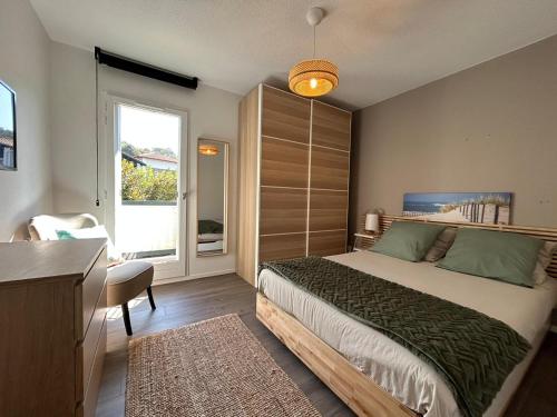 une chambre avec un lit, un bureau et une fenêtre dans l'établissement T2 rénové avec terrasse, à 300m de la plage de Socoa - FR-1-239-1093, à Ciboure