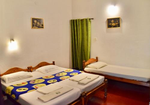 two beds in a room with green curtains at Marari Beach Villas in Mararikulam