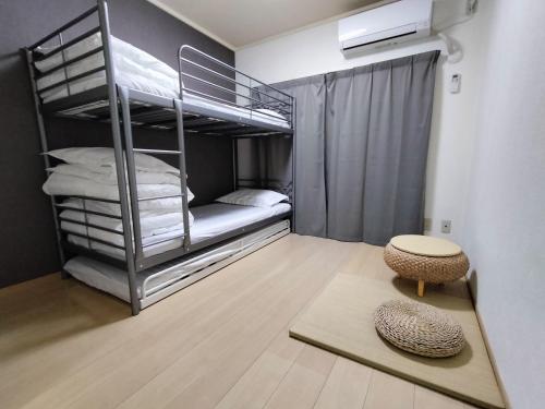 a room with two bunk beds and a table at avanti house大橋A3 in Shiobaru