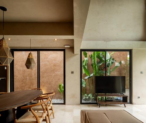 a living room with a tv and a large window at Arvatya Villas Bingin by Blacksand in Badung