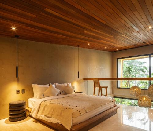 a bedroom with a large bed with a wooden ceiling at Arvatya Villas Bingin by Blacksand in Badung