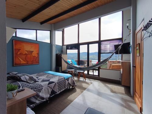 a bedroom with a hammock in a room with windows at Casa Boutique Abadia de Tomine in Guatavita