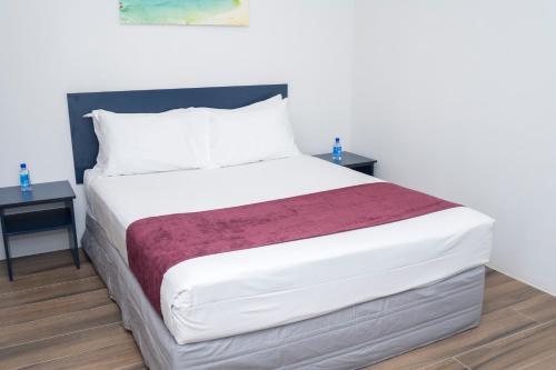 a bedroom with a large white bed with two tables at Garden Apartments in Nadi