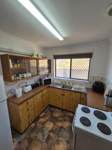 a kitchen with wooden cabinets and a white stove top oven at Champion Bay Beach Unit, with own carport, in Geraldton