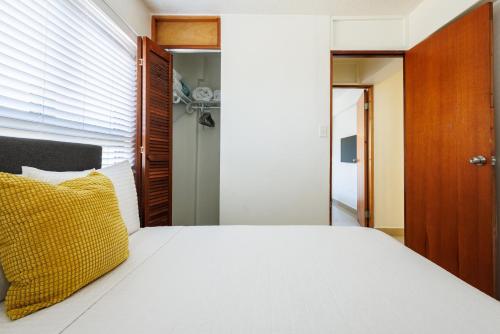 a bedroom with a white bed with a yellow pillow at Avila Suites in San Juan