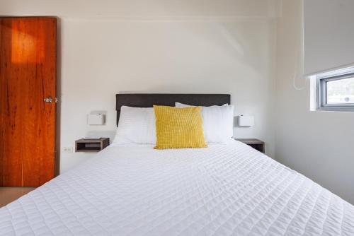 a white bed with a yellow pillow on it at Avila Suites in San Juan
