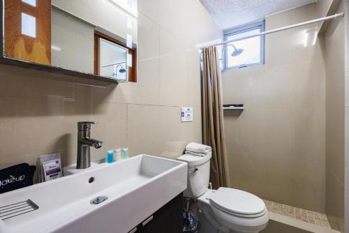 a white bathroom with a toilet and a sink at Avila Suites in San Juan
