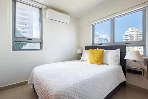 a bedroom with a white bed and two windows at Avila Suites in San Juan