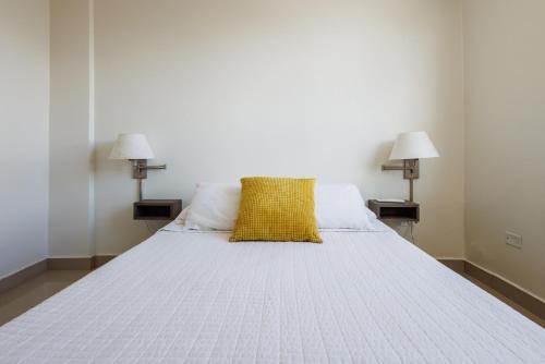 a bedroom with a bed with a yellow pillow on it at Avila Suites in San Juan