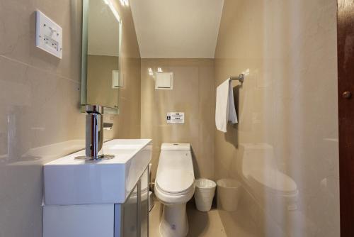 a bathroom with a toilet and a sink and a mirror at Avila Suites in San Juan