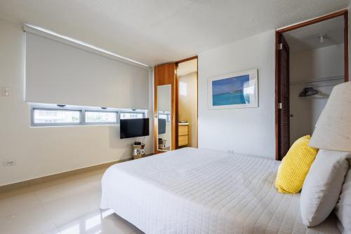 a bedroom with a white bed and a television at Avila Suites in San Juan