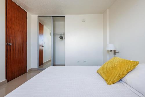 a bedroom with a bed with a yellow pillow on it at Avila Suites in San Juan