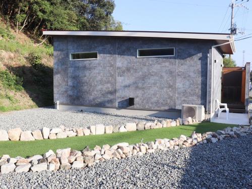 a house with a gravel yard in front of it at ちょこっとヴィラMaestro in Tusi