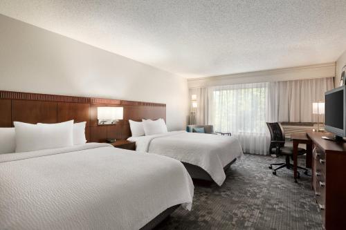 a hotel room with two beds and a desk at Courtyard Lubbock in Lubbock
