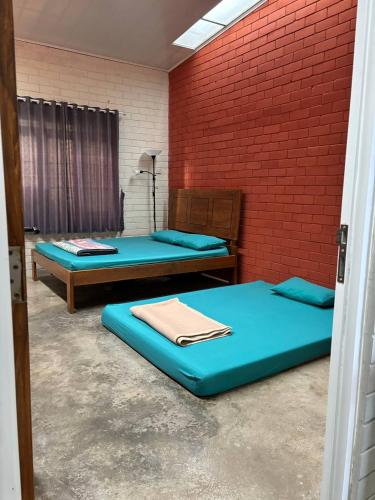 a room with two beds and a brick wall at Villa Tagar Hidayah in Ciwidey