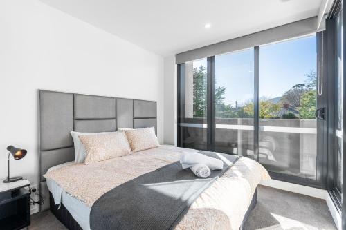 a bedroom with a large bed with a large window at Modern Apartment next to Canberra Centre in Canberra