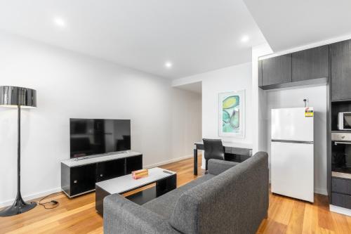 a living room with a couch and a tv and a table at Modern Apartment next to Canberra Centre in Canberra