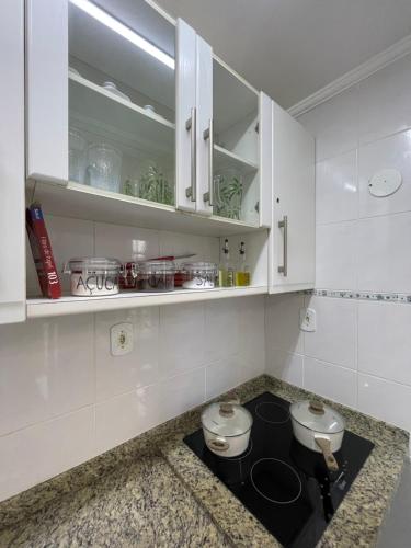 a kitchen with white cabinets and a stove top oven at Pé na Areia Praia das Toninhas - Villagio 17 in Ubatuba