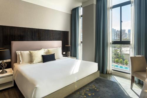 曼谷Metropolis Suites Bangkok, Tapestry Collection by Hilton的卧室里有一张白色的大床和一扇窗户