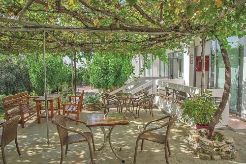 a patio with tables and chairs under a tree at Megim Hotel in Palaiochóra