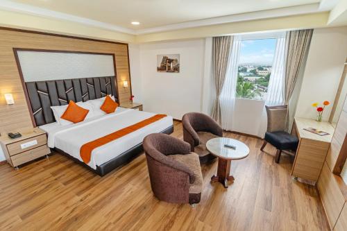 a hotel room with a bed and a table and chairs at Sterling V Grand Madurai in Madurai