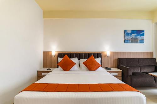 a bedroom with a bed with orange pillows and a couch at Sterling V Grand Madurai in Madurai