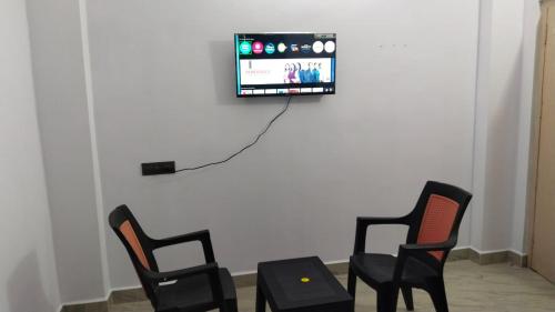 two chairs and a table with a tv on a wall at Rest N' Refresh Homes in Visakhapatnam