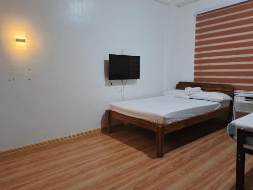 a bedroom with a bed and a tv on the wall at Montecarlo Townhouse Residences in Masbate