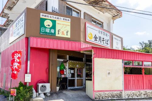 a red building with signs on the front of it at 恩納村一棟貸し ビーチや飲食店徒歩圏内 最大6名 Ciel希望ヶ丘A棟 in Onna