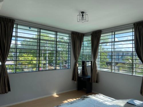 a bedroom with large windows with a bed and a desk at Sandakan Js homestay in Sandakan