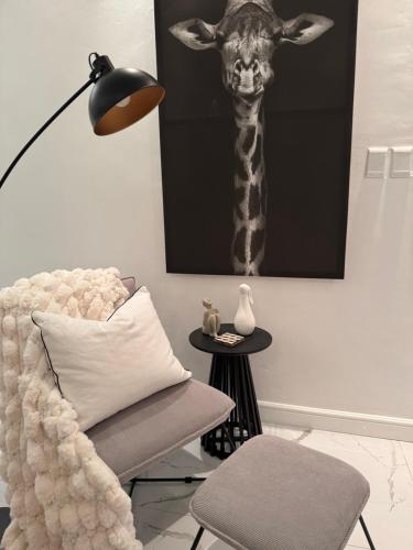 a giraffe picture hanging on a wall next to a chair at Luxurious Apartment in Cape Town