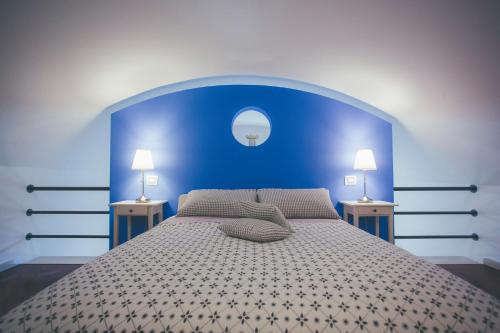 a blue bedroom with a large bed with two lamps at I Sassi Di Teopista in Matera