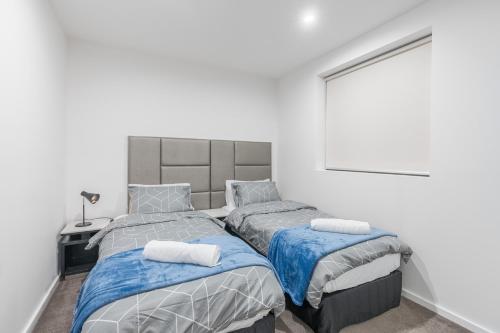 a bedroom with two beds with blue and gray sheets at Modern Apartment next to Canberra Centre in Canberra
