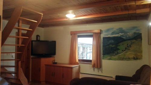 sala de estar con TV y ventana en Lodge In Koprivnik, en Koprivnik v Bohinju