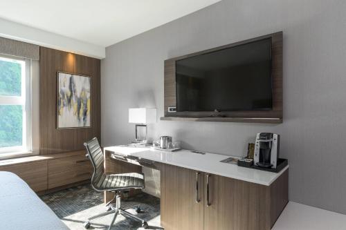 a hotel room with a desk with a television on the wall at Courtyard by Marriott Edgewater NYC Area in Edgewater