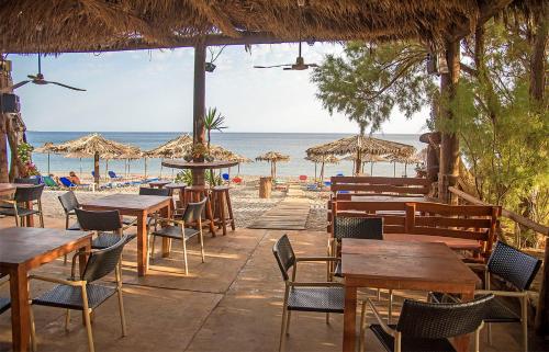 a restaurant on the beach with tables and umbrellas at Megim Hotel in Palaiochóra