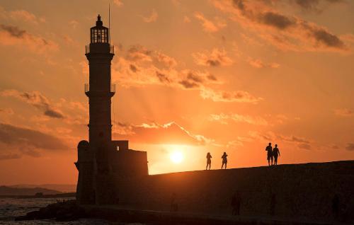 a lighthouse at sunset with people standing on a ledge at Megim Hotel in Palaiochóra