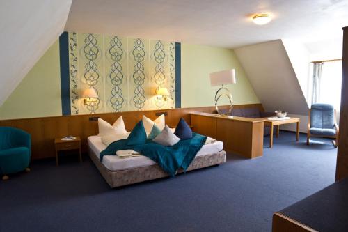 a room with a bed with pillows and a desk at Hotel Berg in Dannenfels