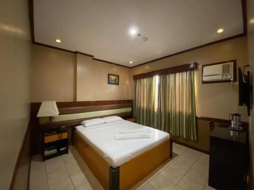 a small bedroom with a bed and a window at Hotel Palwa in Dumaguete